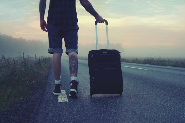 man-walking-on-the-road-holding-black-luggage-during-sunset-160483